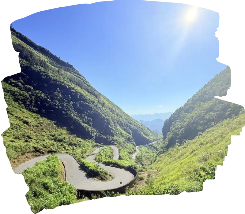A breathtaking view of the majestic Tham Ma Pass, with its winding curves set against a stunningly clear blue sky. A perfect, sunny day on the Ha Giang Loop tour.