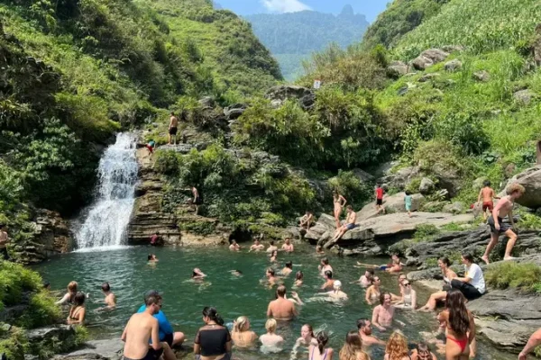 people are swimming at du gia water fall in du gia village in summer