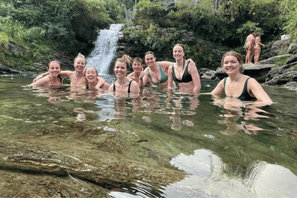International travelers swimming together at Du Gia Waterfall on Ha Giang motorcycle loop